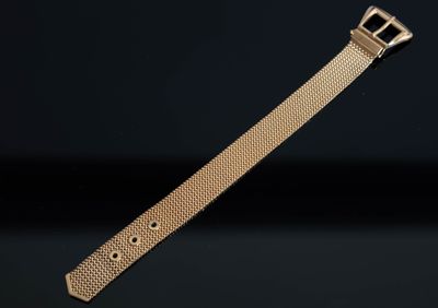 un gros plan d'un bracelet de montre en or sur fond noir
