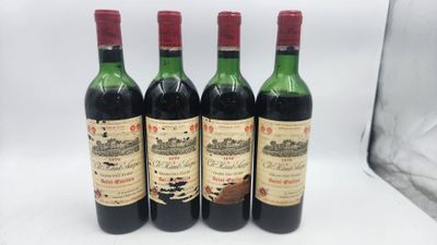quatre bouteilles de vin sont alignées sur une surface blanche
