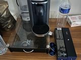 une cafetière posée sur une table, à côté de bouteilles d'eau et d'autres objets