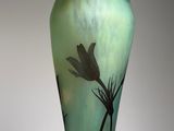 a green vase with a black flower on it