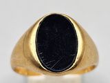 a close up of a gold ring with a black stone