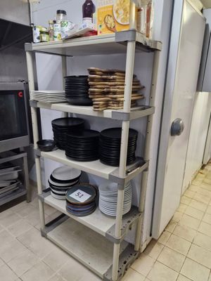 de nombreuses assiettes et casseroles empilées sur une étagère dans la cuisine
