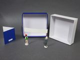 three small figurines of people standing in front of a box
