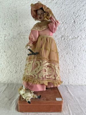 une figurine représentant une femme vêtue d'une robe rose et d'un chapeau