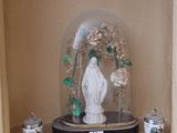 un dôme en verre renfermant une statue, posé sur une étagère