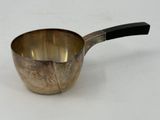 a metal measuring cup with a black handle on a white surface