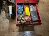 une boîte à outils rouge posée par terre et remplie d'objets divers