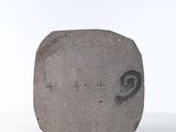 a stone with a face on it sitting on a white surface
