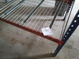 une étagère métallique sur laquelle est accrochée une pancarte, dans un entrepôt