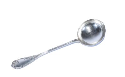 une cuillère en argent avec un manche de cuillère sur une surface blanche