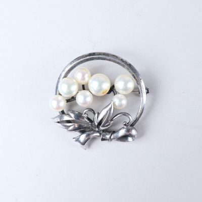une broche composée de perles et de feuilles sur un fond blanc
