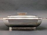 silver plated casserole with lid on stand on grey background