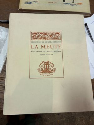un livre posé sur une table, avec un stylo et du papier dessus