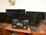 three televisions on a wooden table with speakers on it