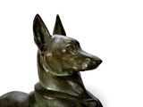statue of a dog laying down on a white surface