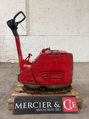 une machine rouge posée sur une palette dans un entrepôt