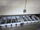 several trays of utensils are lined up in a kitchen