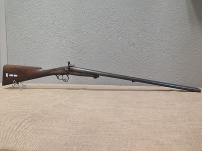 a rifle with a wooden barrel on a table in front of a wall