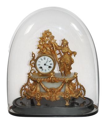 une horloge en or sous un dôme de verre sur une table