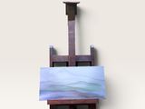 un petit chevalet sur lequel est posé un tableau, posé sur une surface blanche