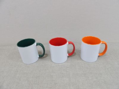 trois tasses à café de couleurs différentes sont alignées sur une table