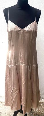 une robe beige posée sur un mannequin contre un mur blanc