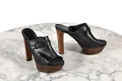 une paire de chaussures en cuir noir posée sur une table en marbre, sur fond blanc