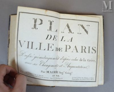 quelqu'un tient un livre ouvert à une page sur laquelle figure une photo de Paris