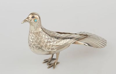 an antique silver bird with turquoise eyes on a white background