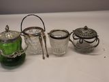 trois théières en verre et en argent et une théière en verre posées sur une table blanche