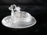 une figurine en verre représentant un chien assis sur une assiette