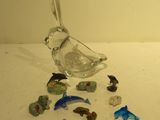 un oiseau en verre posé sur une table, à côté d'autres animaux en verre