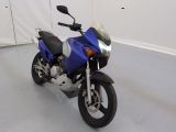 une moto bleue garée dans une pièce aux murs blancs