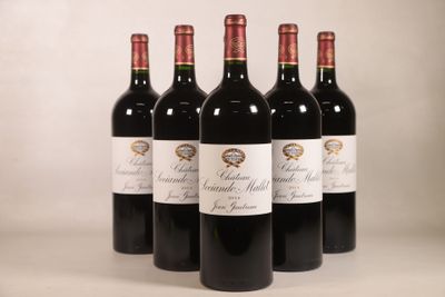 quatre bouteilles de vin rouge sont alignées sur une table