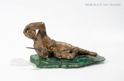 bronze statue of a man laying on a rock with a sword