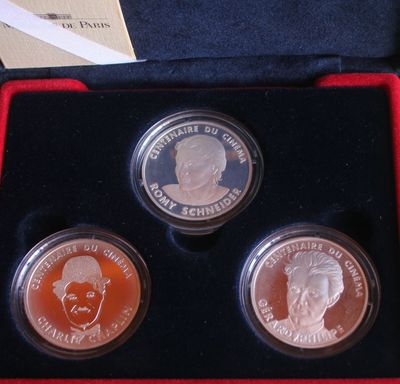 three coins in a red box with a picture of a man and a woman on them
