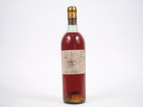 une vieille bouteille de vin posée sur une surface blanche