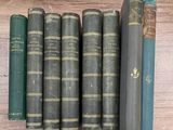 Plusieurs vieux livres sont alignés sur une étagère posée sur un support en bois