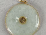 a close up of a gold plated pendant on a white surface
