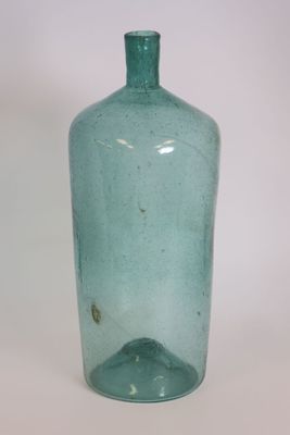 a green glass bottle that is sitting on a table