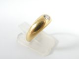 yellow gold ring with a single diamond on a clear acrylic stand