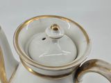 a white and gold tea pot with a gold rim