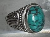 une bague en argent sertie d'une turquoise, posée sur une table