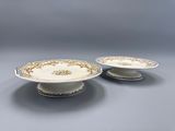 deux assiettes blanches et dorées, ornées de motifs dorés sur un fond gris