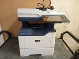 the printer is sitting on top of the table next to the chair