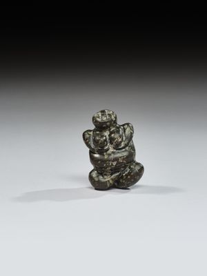 une petite figurine en bronze représentant un singe perché sur un rocher