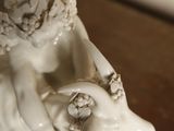 a white statue of a woman with a goat on a table