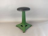 a green stool with a black leather seat on it
