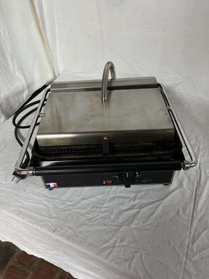 une grille argentée munie d'une poignée, posée sur un drap blanc