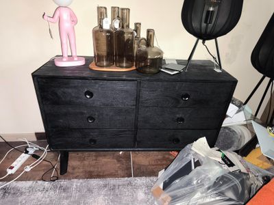 une commode sur laquelle sont posées des bouteilles et une lampe